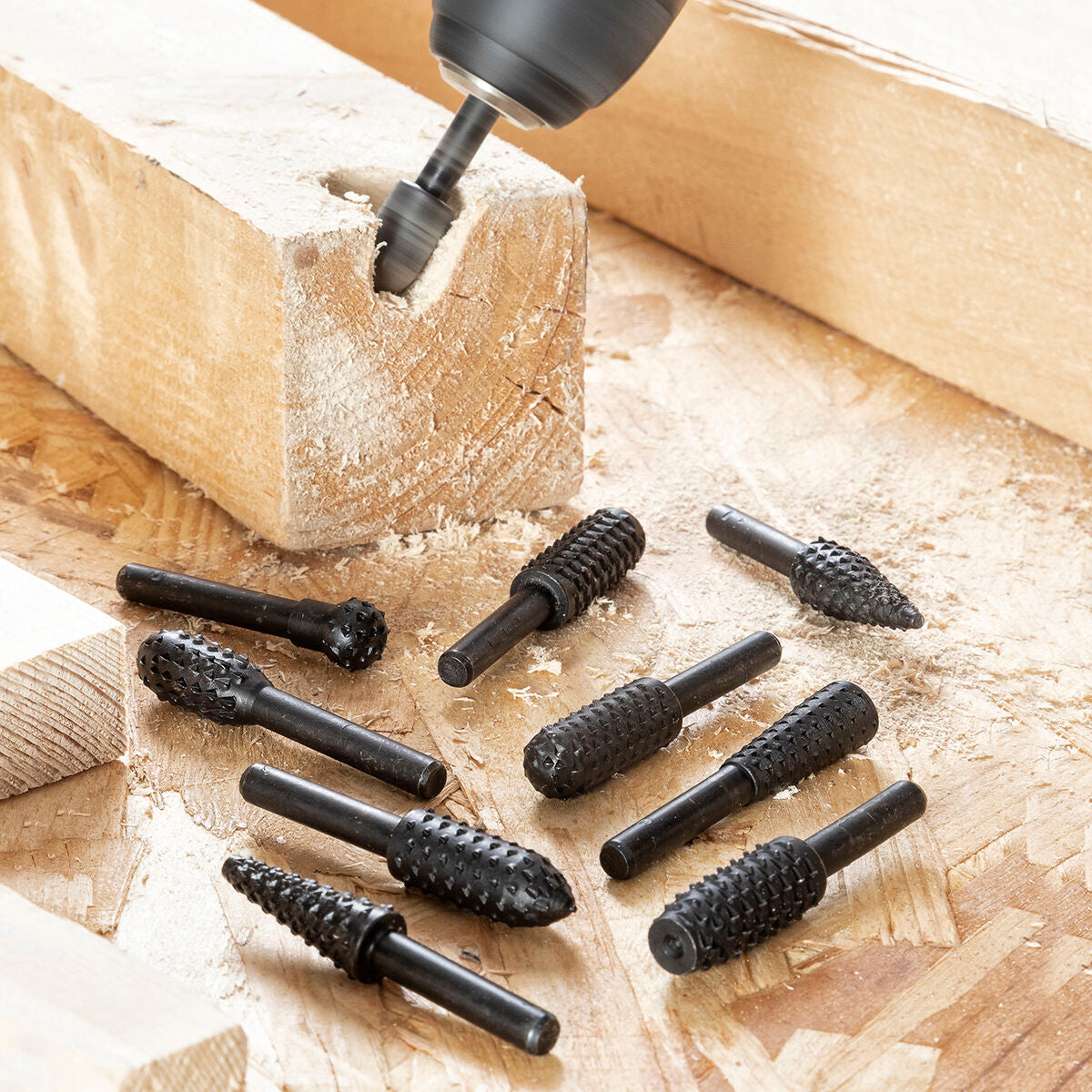 Una punta da trapano lavora un pezzo di legno, con diversi attrezzi nelle vicinanze.