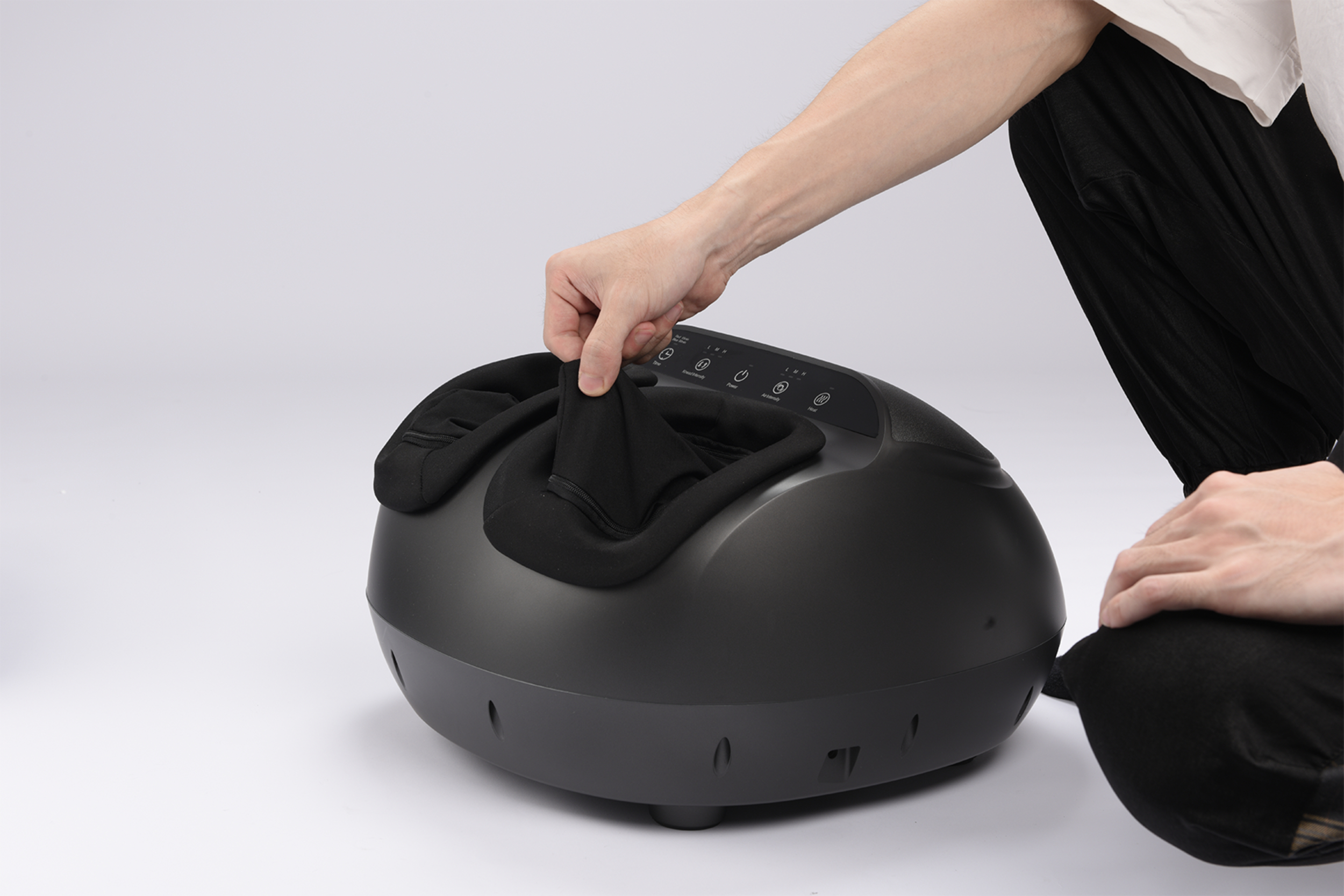 Eine Hand passt die schwarze Polsterung eines schwarzen Fußmassagegeräts an.