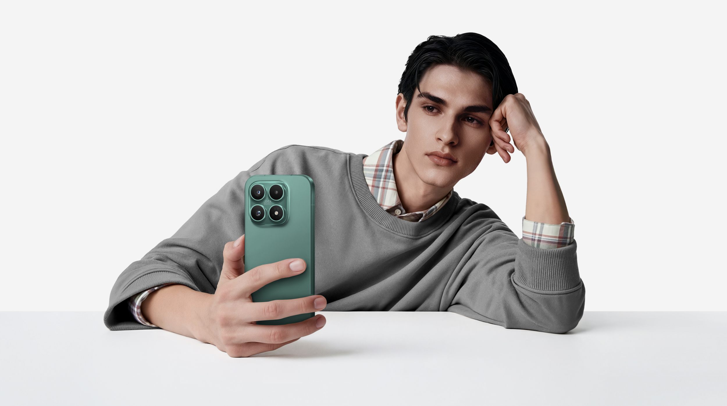 Un hombre sostiene un smartphone verde ante un fondo blanco.