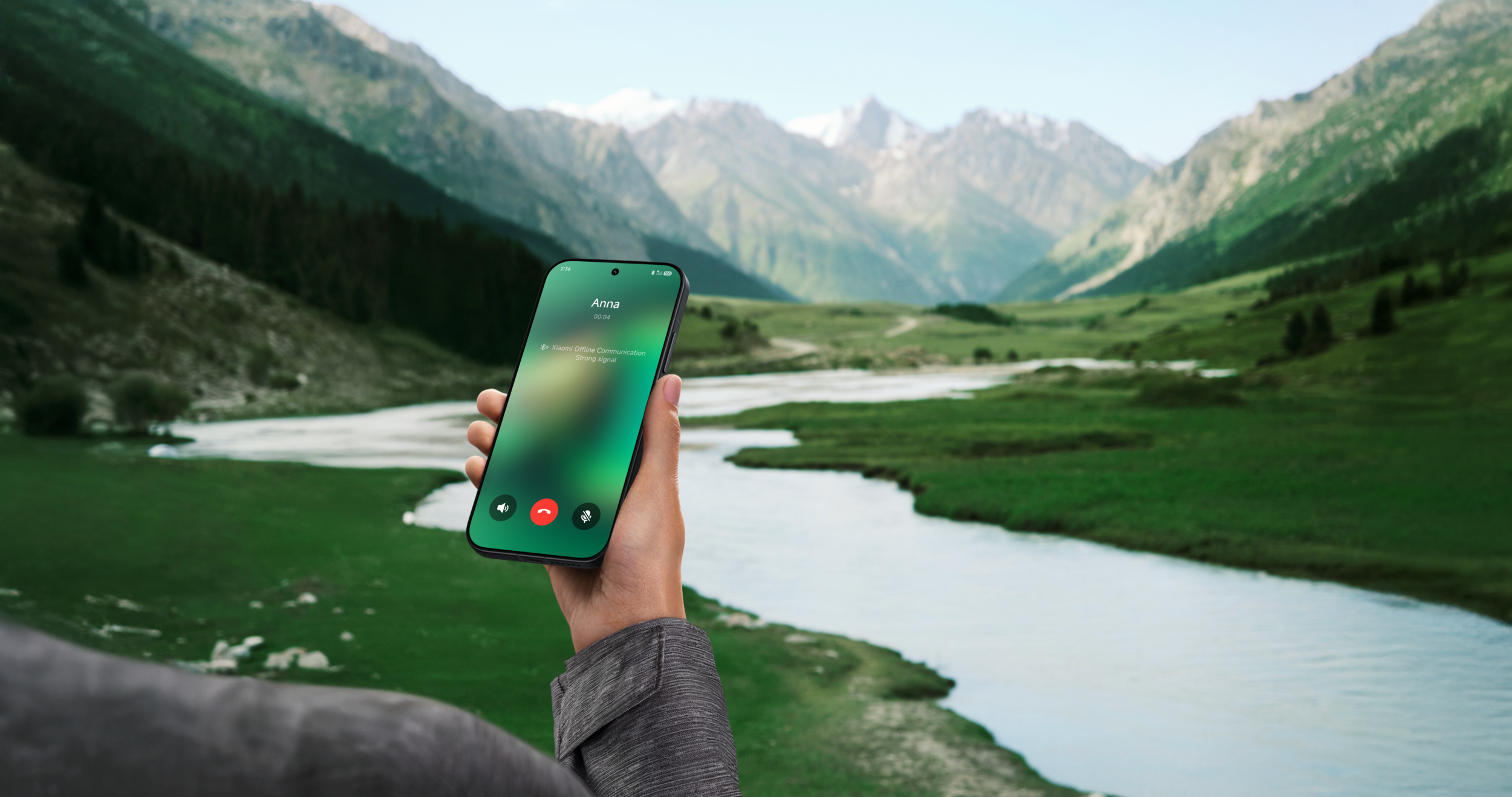 Mano sostiene smartphone con pantalla de llamada ante paisaje montañoso con río.