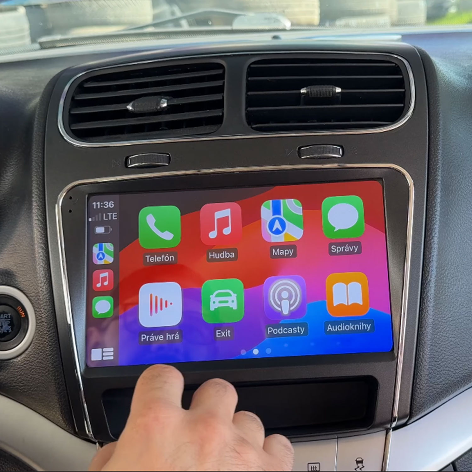 Palec dotyka ekranu samochodu z interfejsem Apple CarPlay.