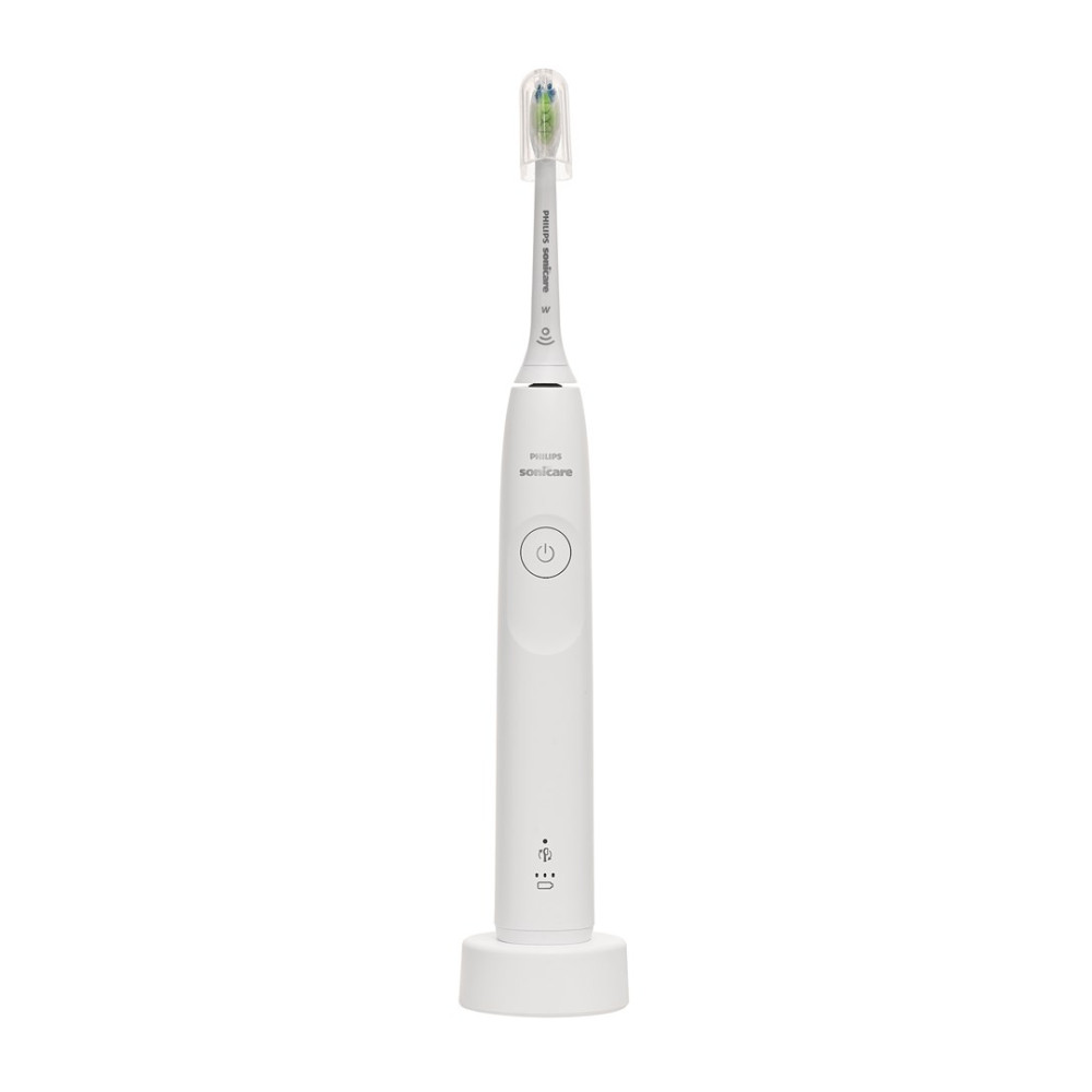 Biała szczoteczka elektryczna Philips Sonicare z przezroczystą nakładką stoi na białej ładowarce.