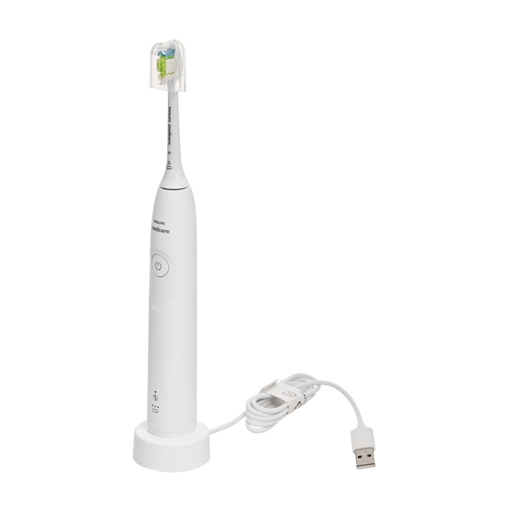 Biała szczoteczka elektryczna ze stacją ładującą i kablem USB, na białym tle.