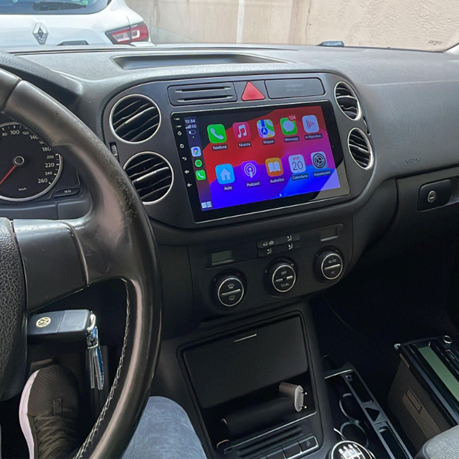 Deska rozdzielcza samochodu z ekranem CarPlay, kierownicą i nawiewami.