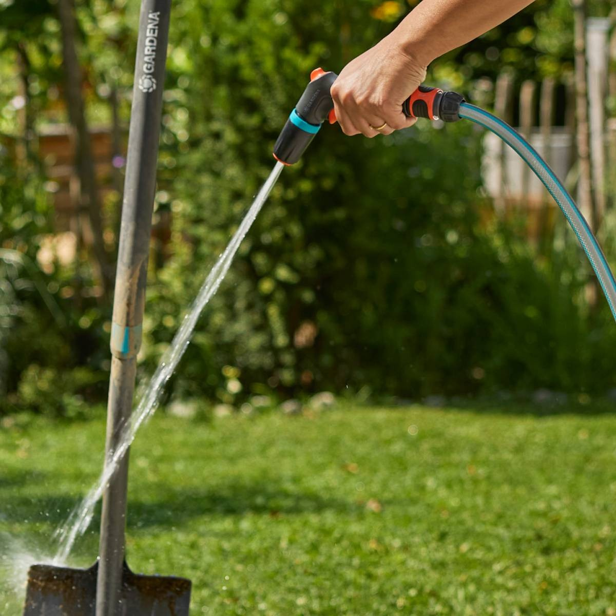 Mano spruzza acqua su una pala in un giardino.