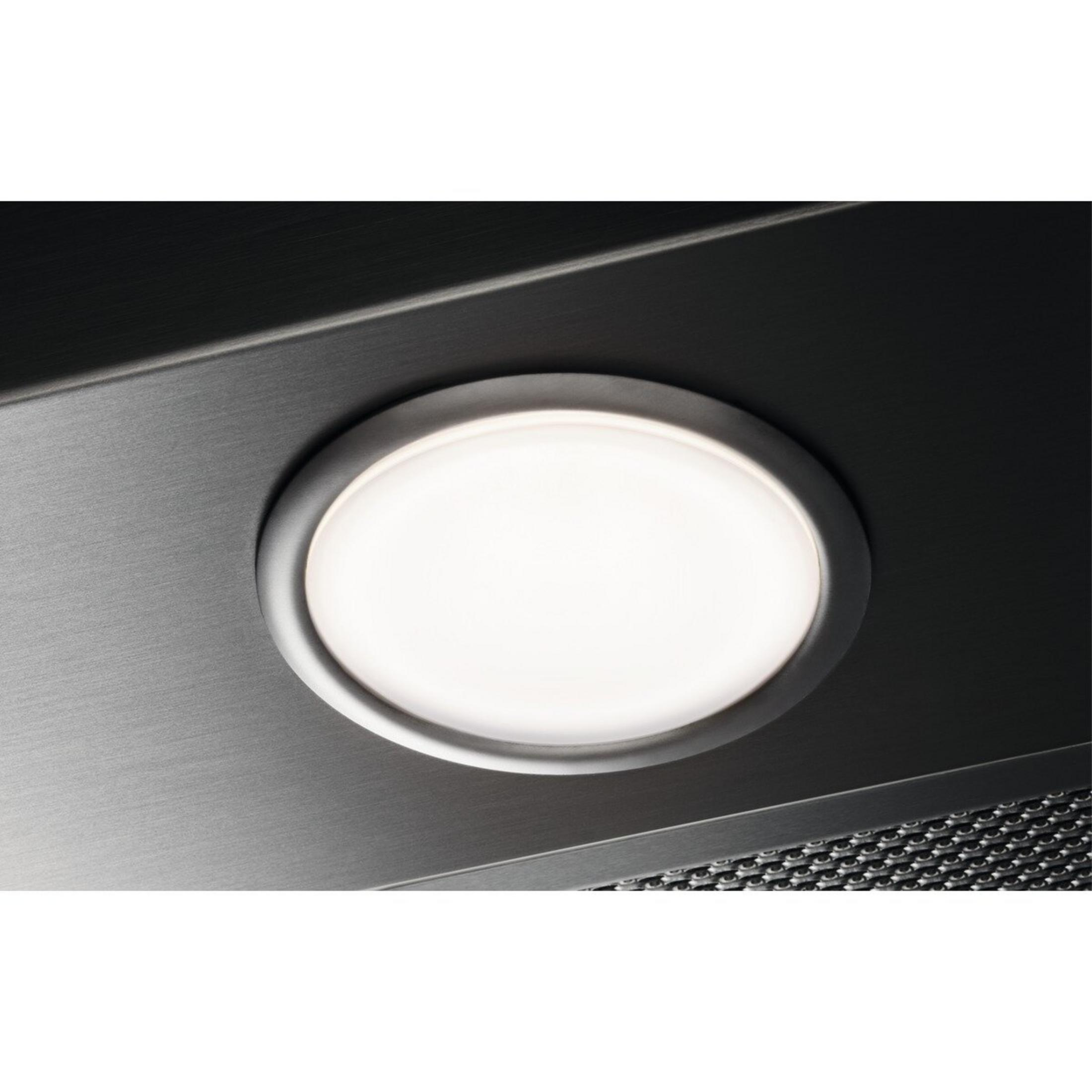 Ein hell erleuchteter ovaler Lichtpunkt in einem Dunstabzugshaubenfilter aus Metall.