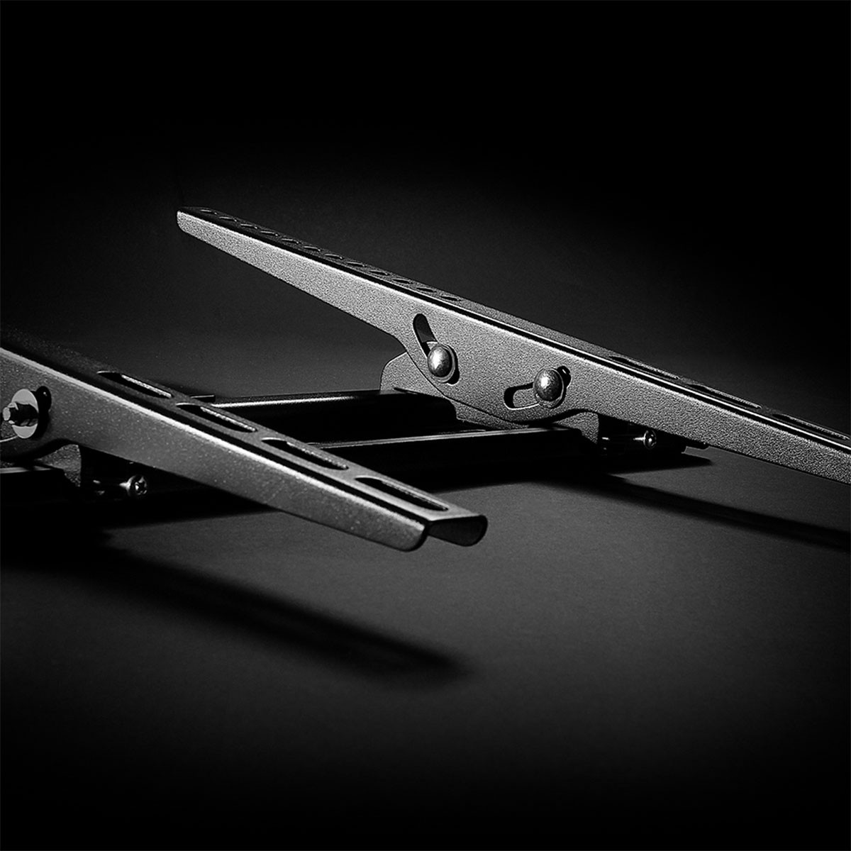 Due bracci metallici scuri con rivetti e fessure su sfondo nero.
