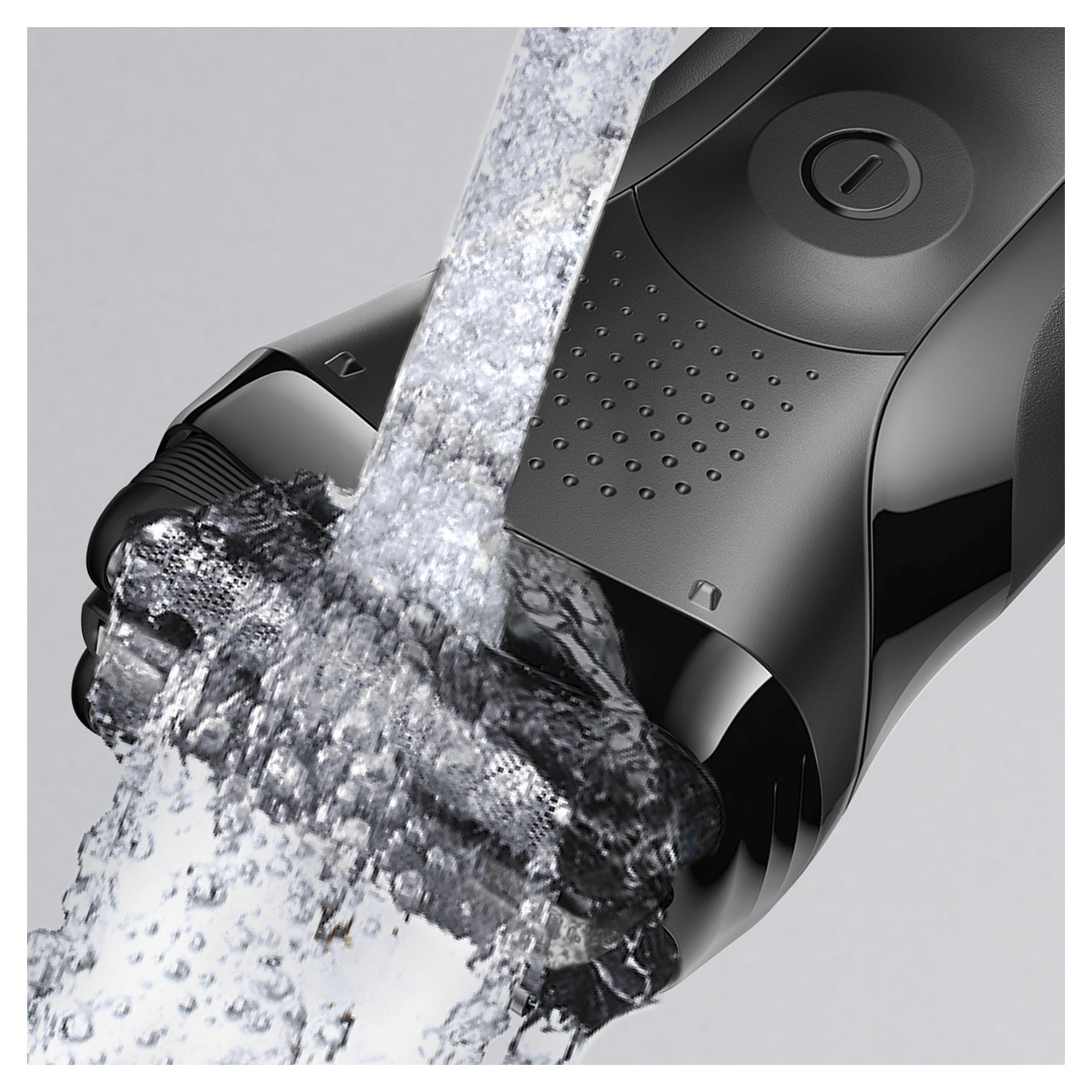 Un rasoio elettrico nero viene sciacquato sotto acqua corrente.