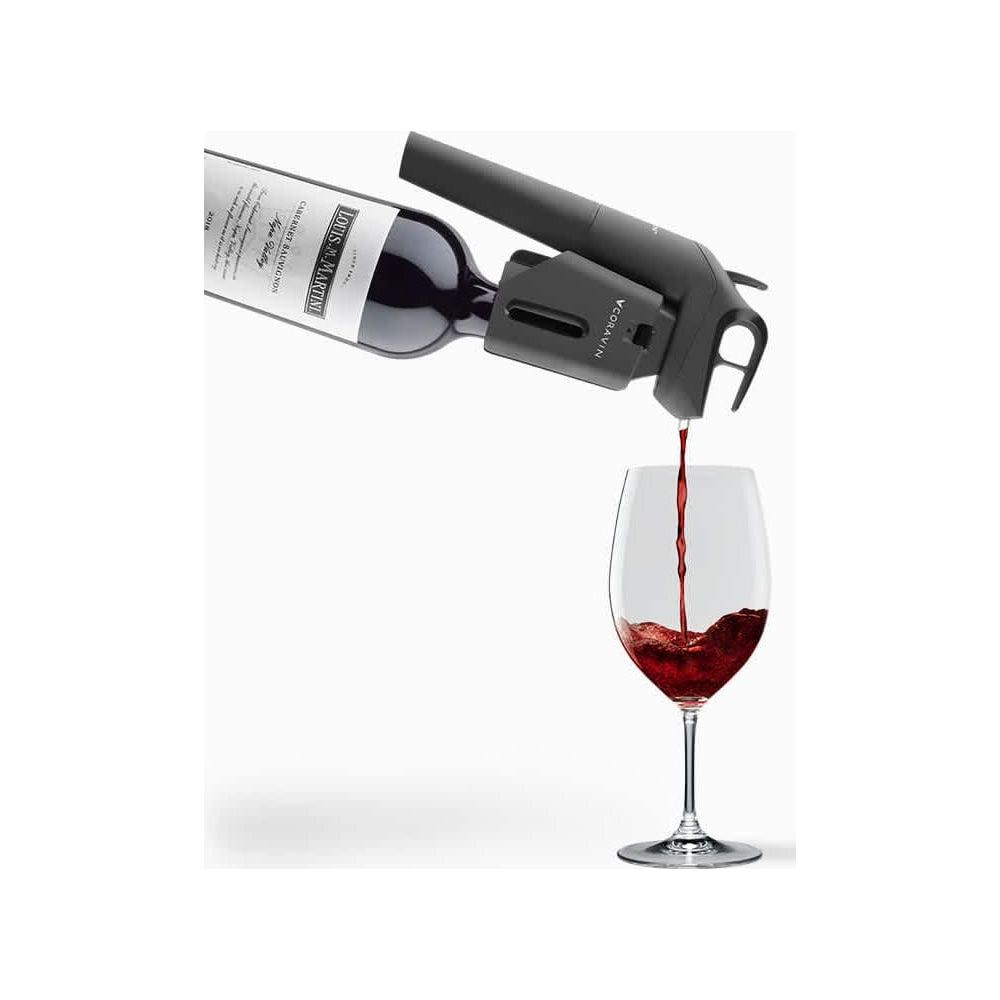 Dozownik wina nalewa czerwone wino z butelki do kieliszka.