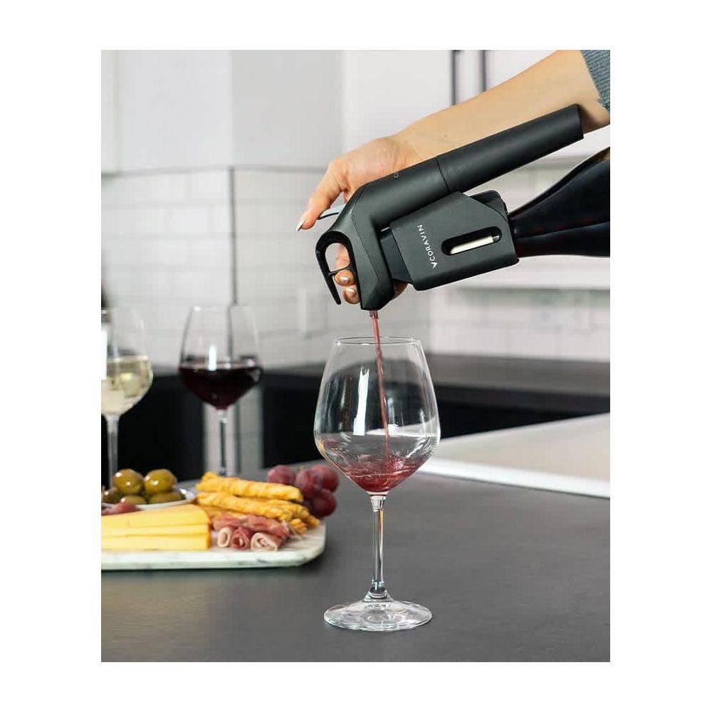 Czerwone wino nalewane do kieliszka urządzeniem Coravin. Deska serów w tle.