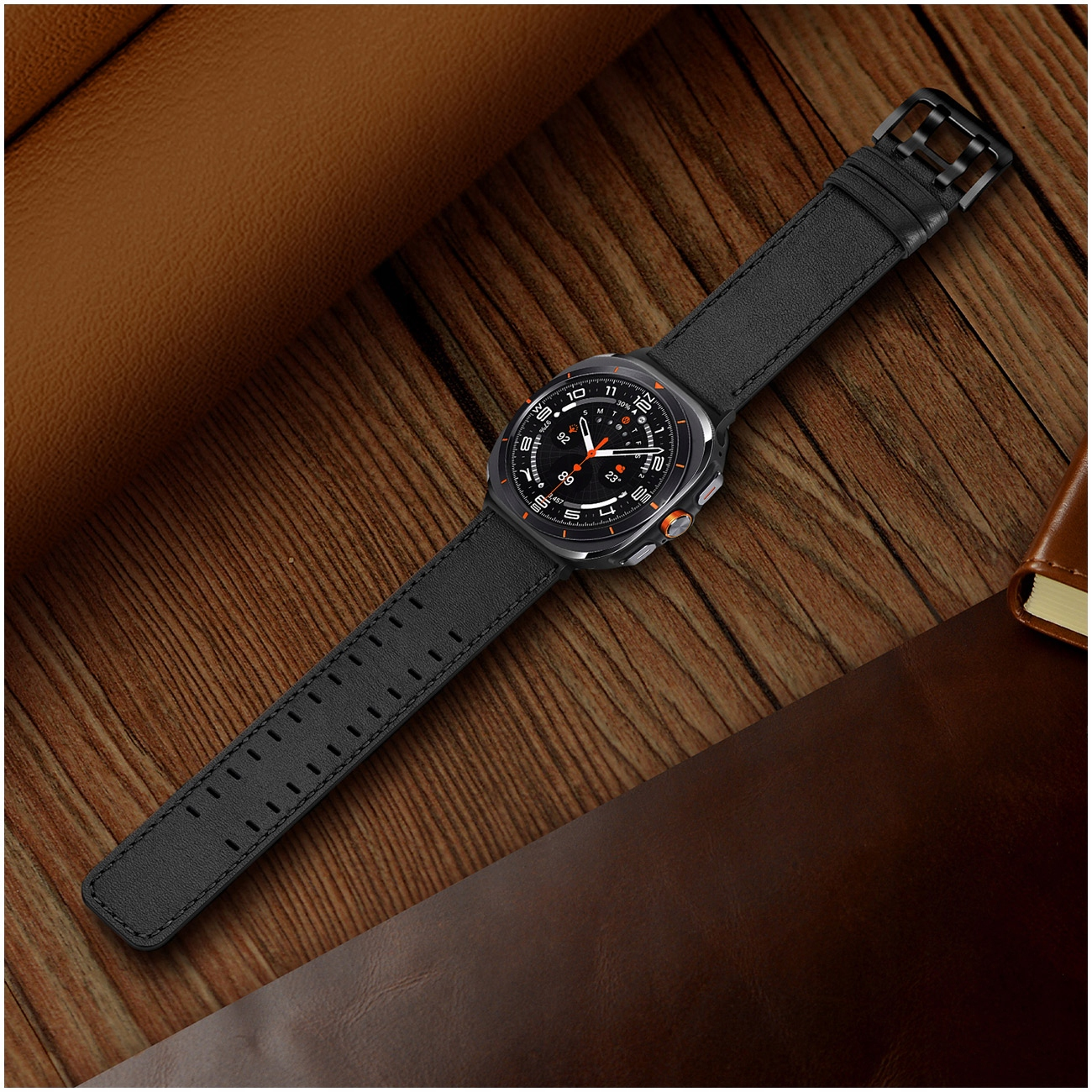 Czarny smartwatch z perforowanym paskiem leży na drewnianej powierzchni.