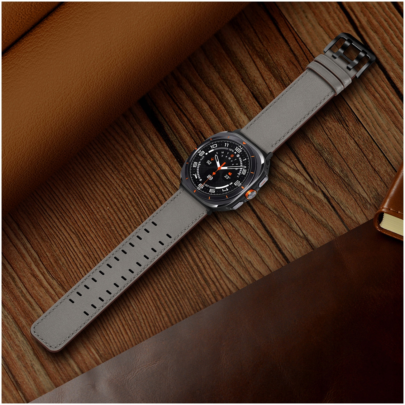 Szary smartwatch z czarną tarczą na drewnianym tle.