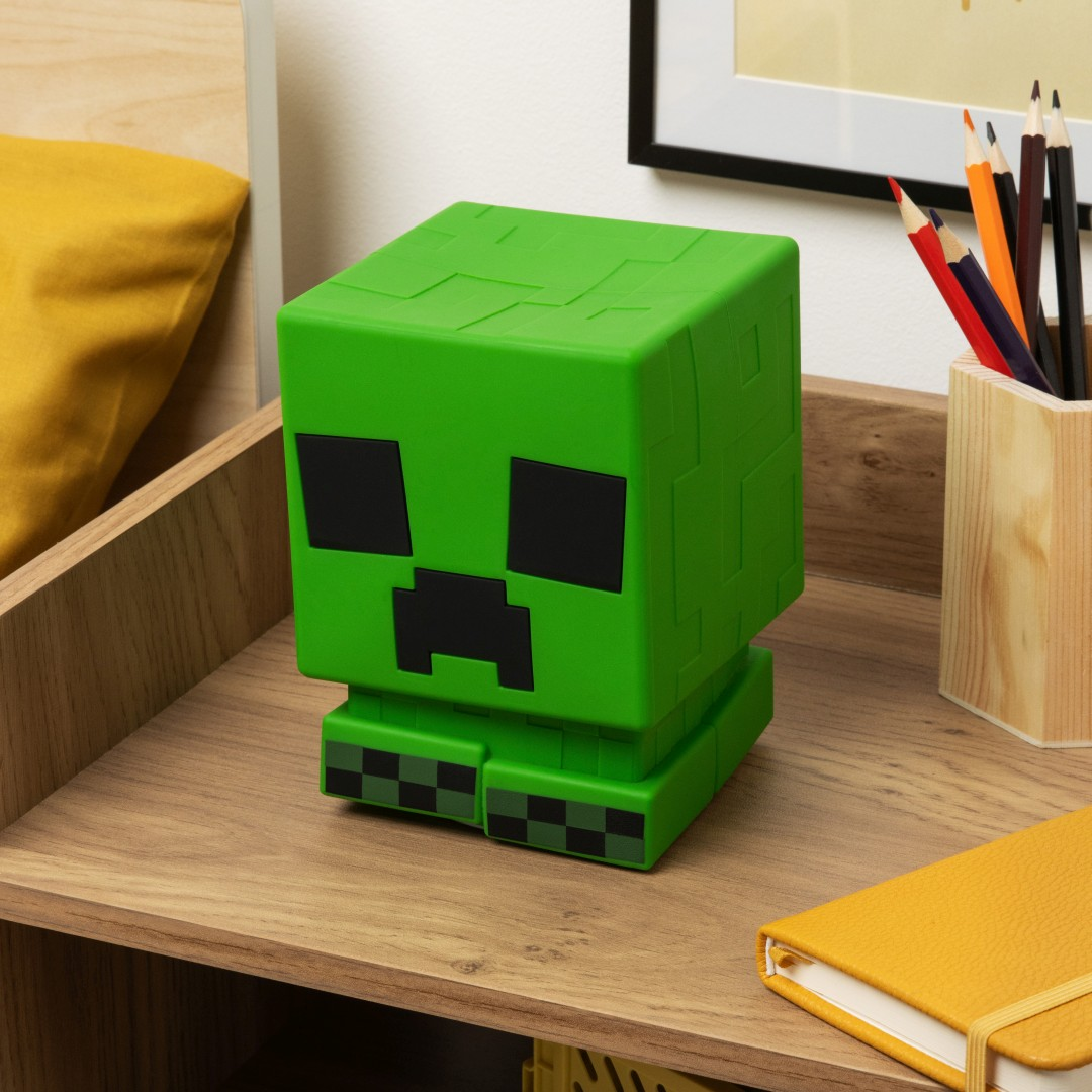 Zielony Creeper z Minecraft na drewnianym biurku z artykułami piśmienniczymi.