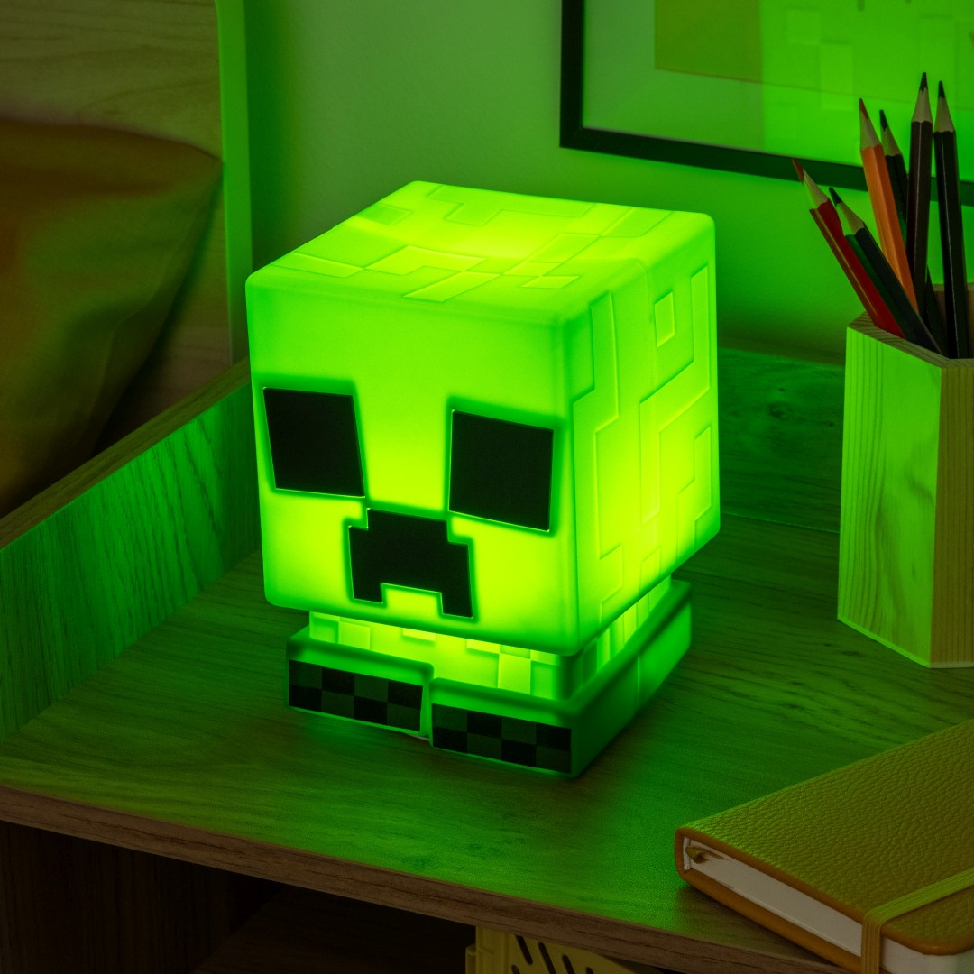 Zielona lampa Minecraft Creeper na drewnianym biurku z ołówkami i notatnikiem.