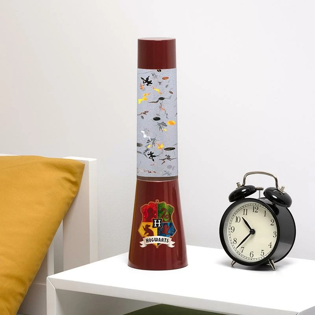 Lampa Harry Potter z logo Hogwartu i budzik na białym stole.