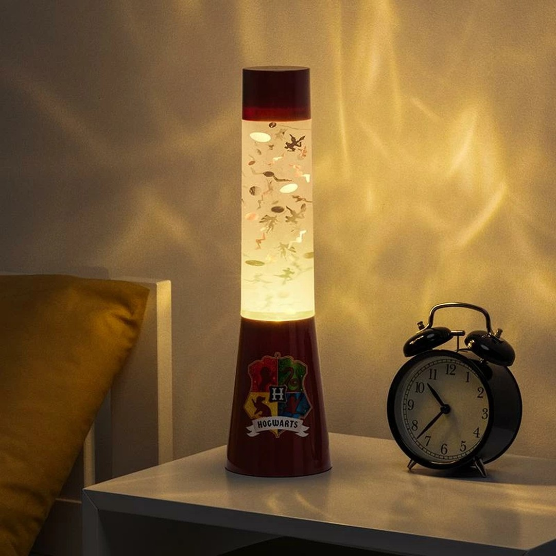 Lampa lawowa w stylu Hogwartu z brokatem i zabytkowym budzikiem na szafce nocnej.