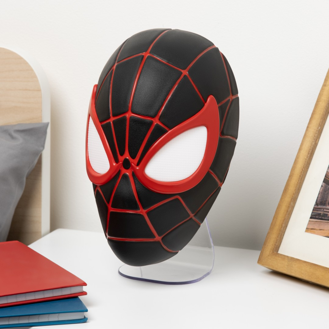 Czarna maska Spidermana z czerwonymi liniami i białymi oczami na stojaku.