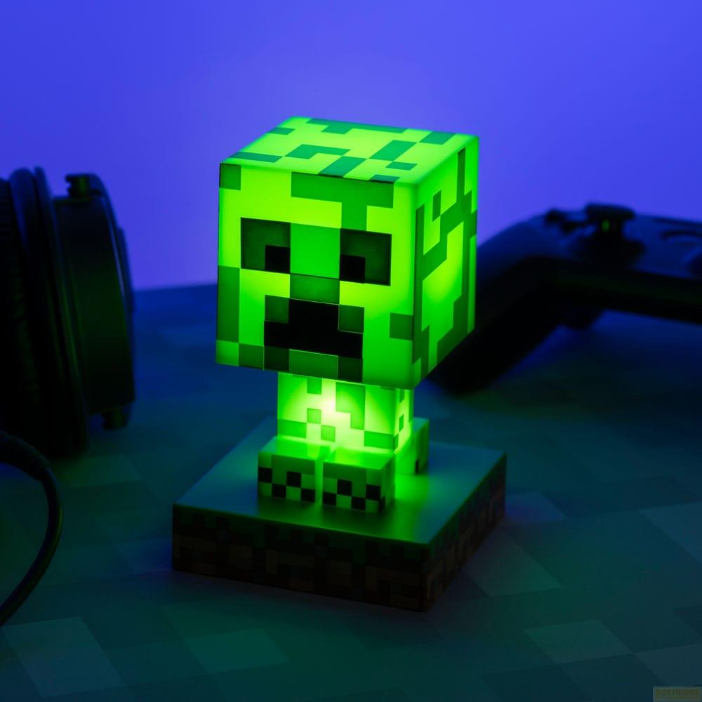 Zielona lampa w kształcie Creepera z Minecraft na podstawie, ze słuchawkami i kontrolerem.
