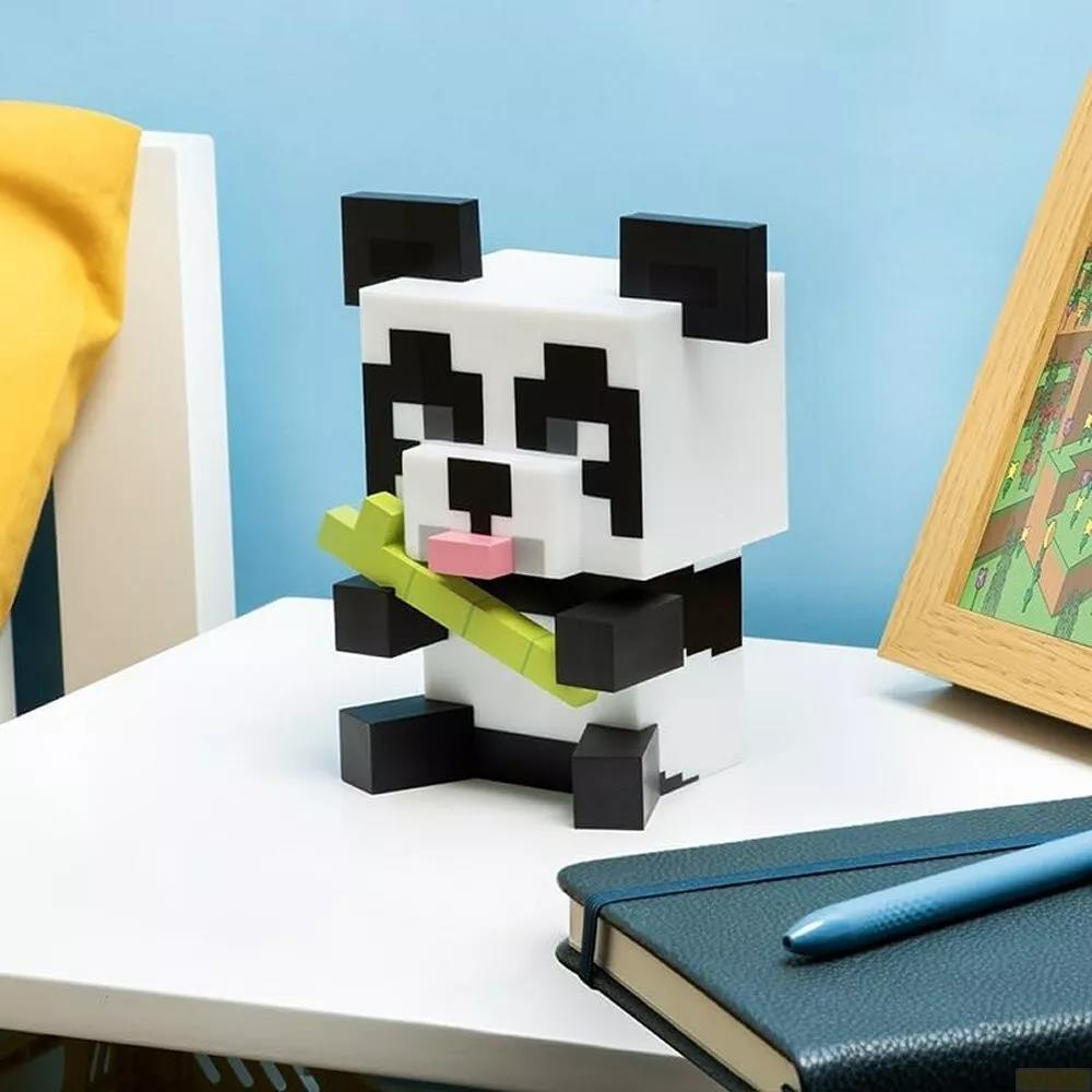 Pikselowata panda trzymająca bambus siedzi na białym stole obok notatnika.