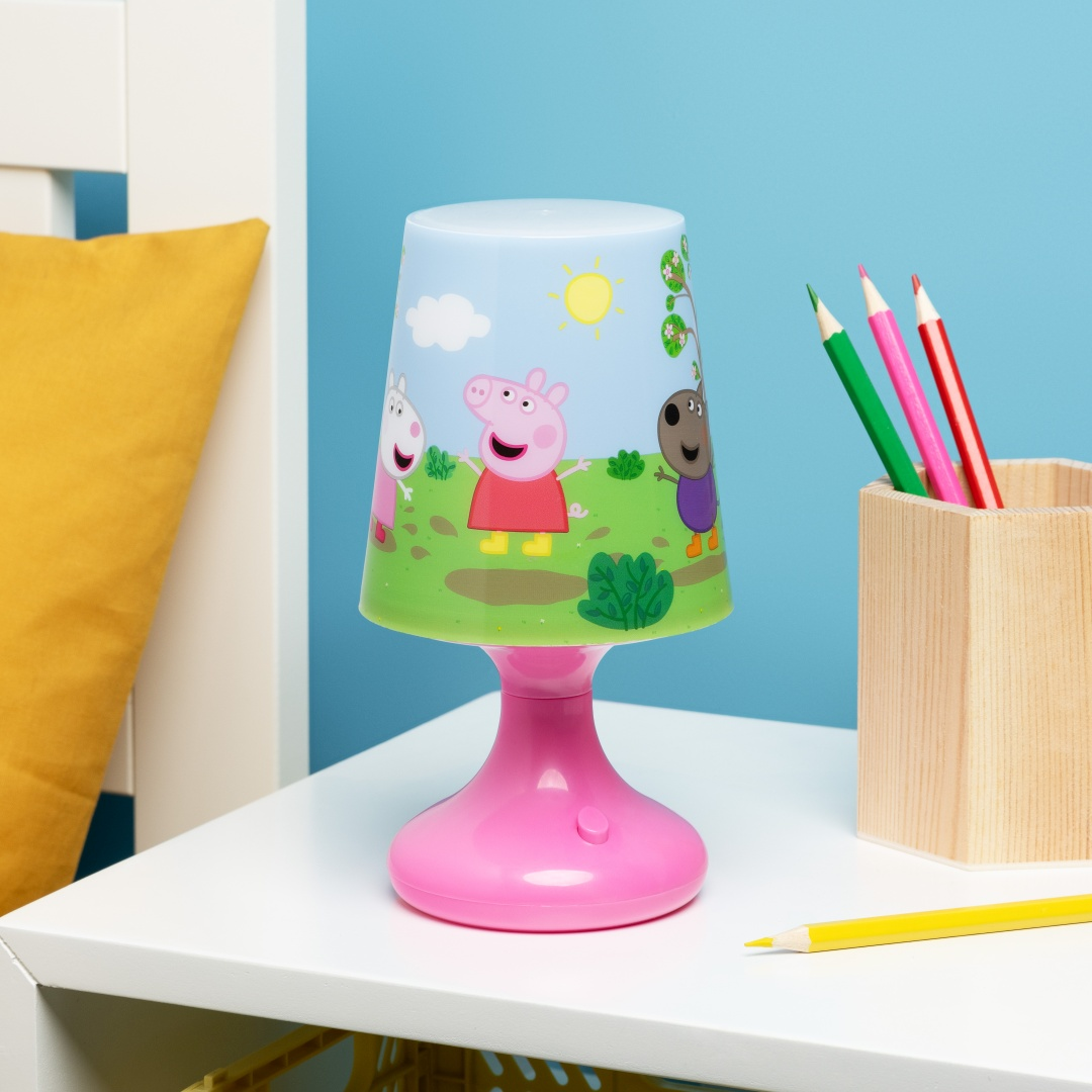 Lampa Peppa Pig stoi na białym stole z kolorowymi kredkami.