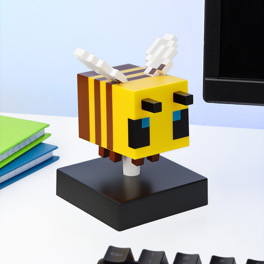 Wyświetlacz pszczoły Minecraft na czarnej podstawie, z książkami i klawiaturą.