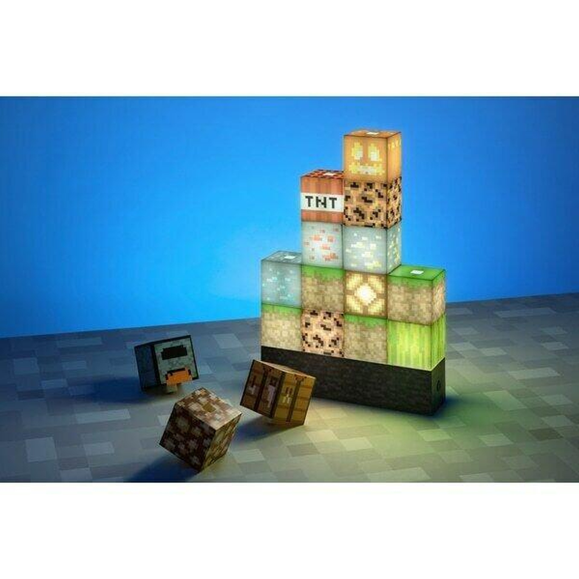 Bloki Minecraft jak TNT, dynia i kamień na niebieskim tle.