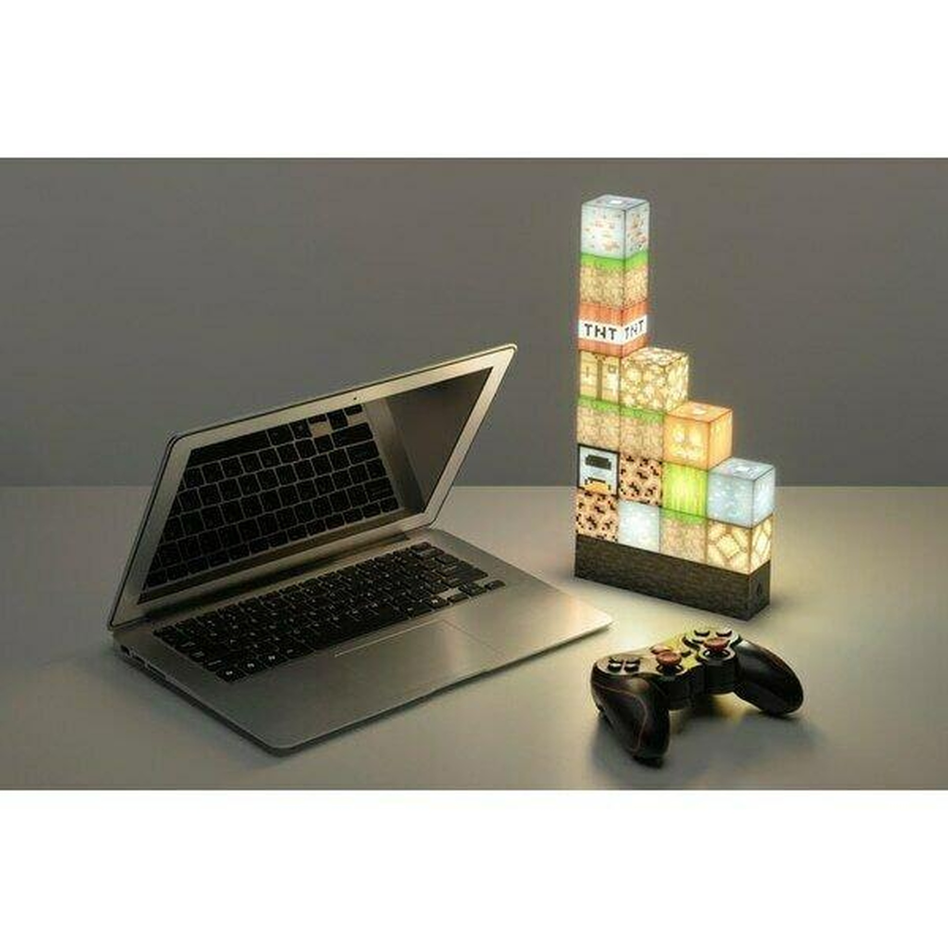 Laptop, kontroler i wieża z lamp Minecraft na stole.