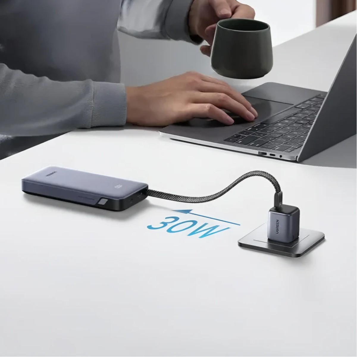 Un uomo digita su un laptop mentre un caricabatterie e un power bank sono collegati.