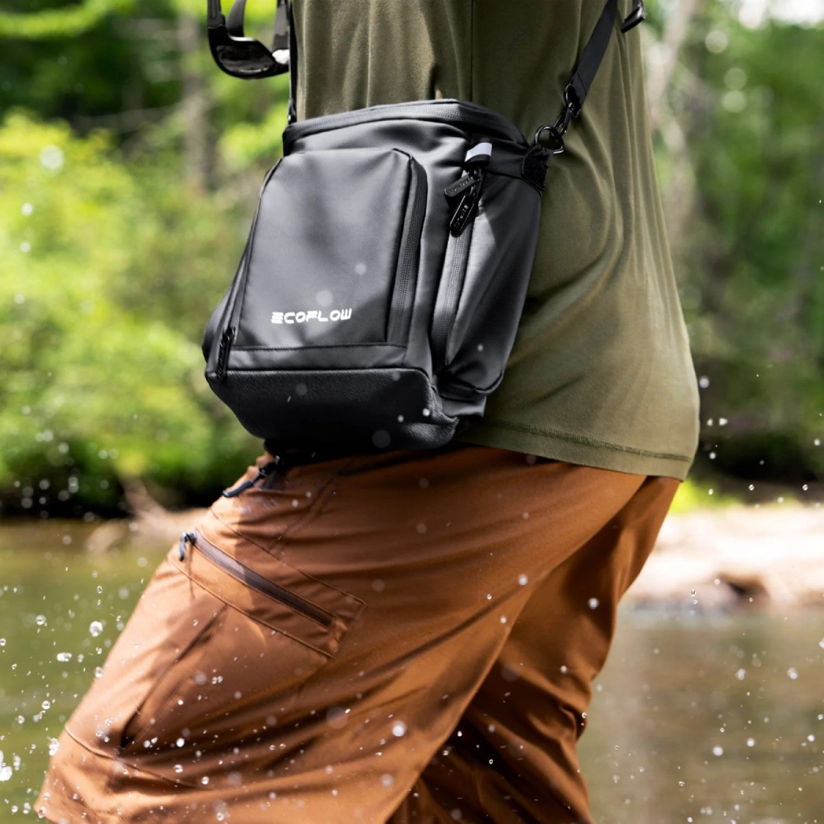 Persona con borsa nera e pantaloni marroni cammina nell'acqua.