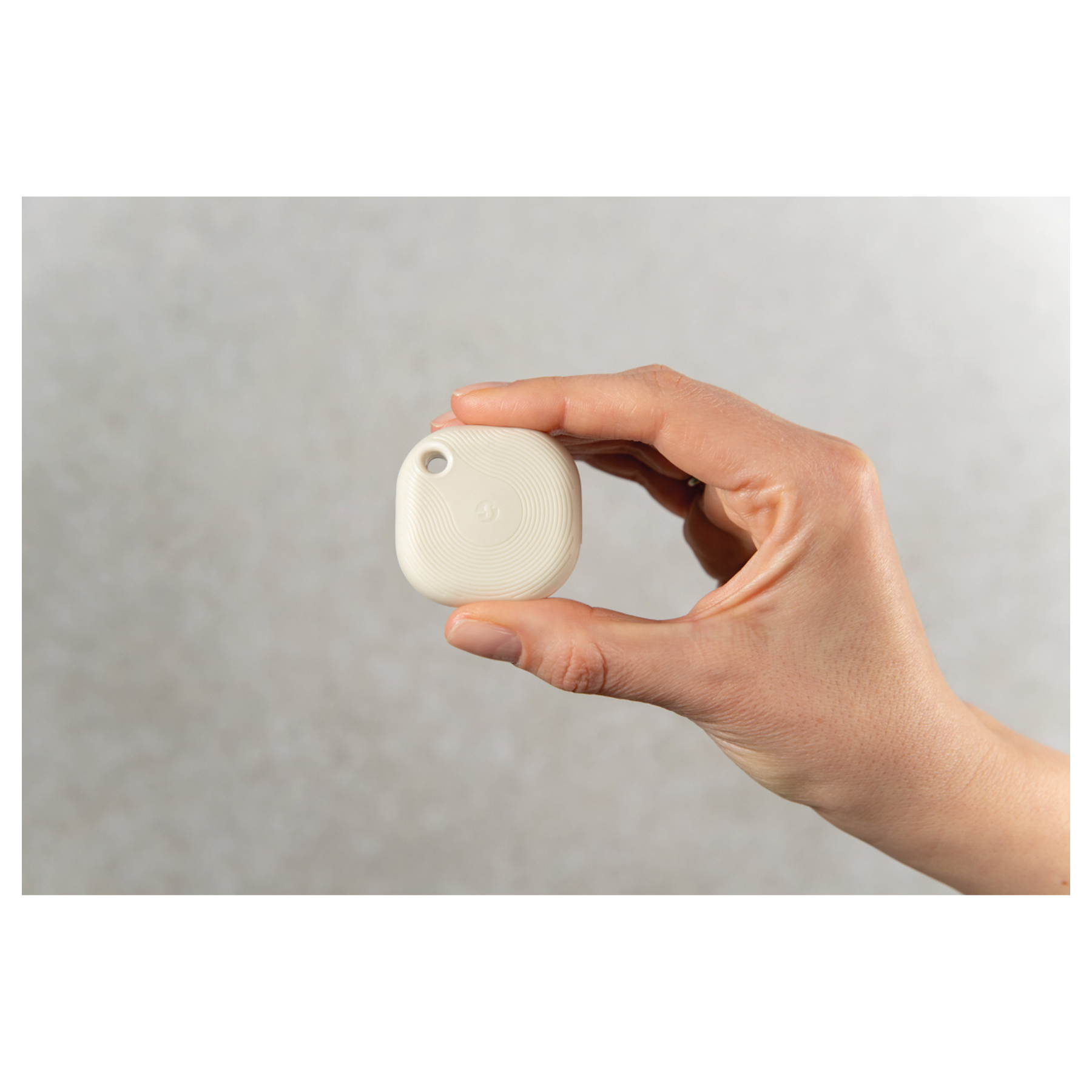 Une main tient un petit objet rond de couleur crème avec des rainures.