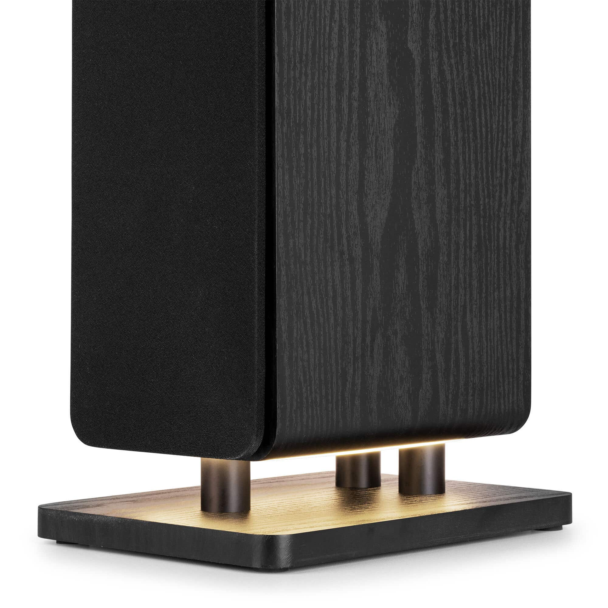 Altavoz negro sobre base de madera con patas metálicas e iluminación.