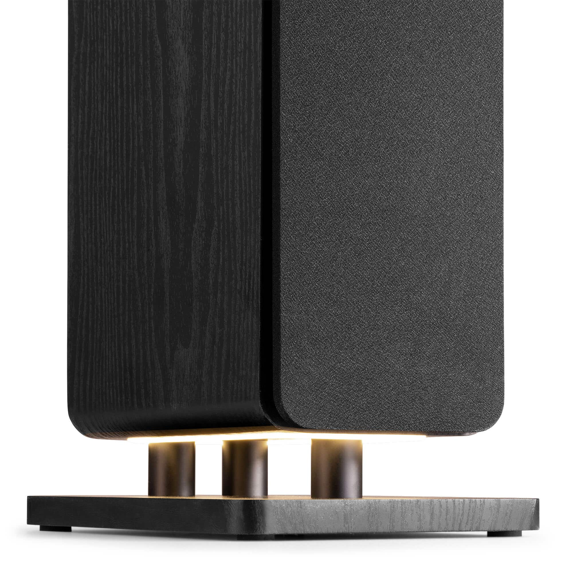 Un altavoz negro con veta de madera y cubierta de tela sobre tres pilares.
