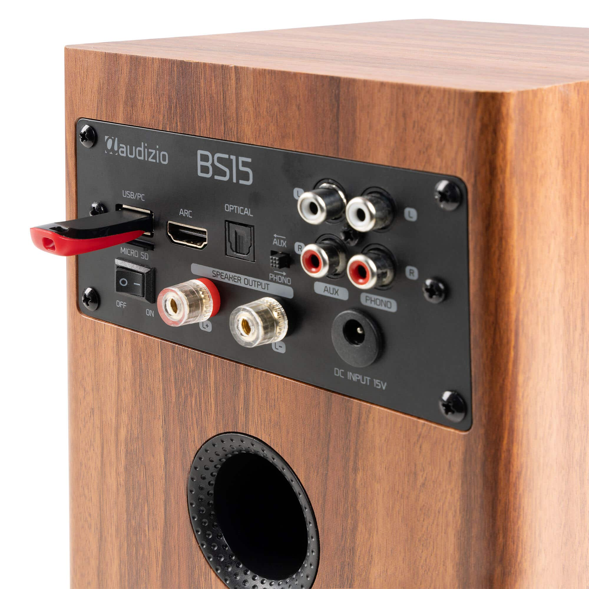 Parte trasera de un altavoz de madera con conexiones como USB, HDMI, Óptica, RCA y salida de altavoz.