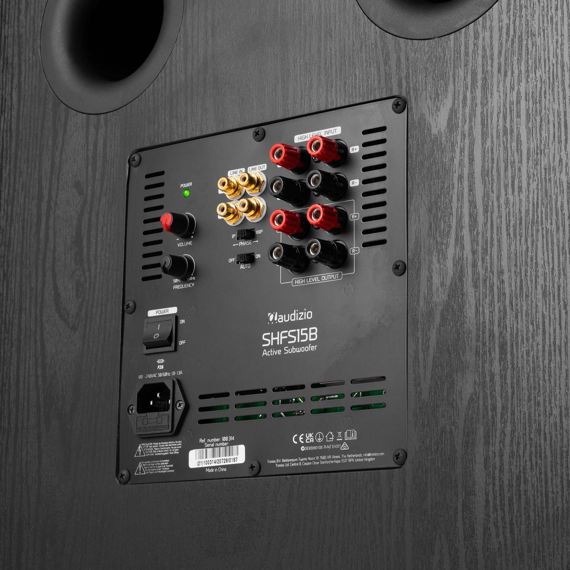 Panel trasero de un subwoofer negro con conexiones, perillas y etiquetas.