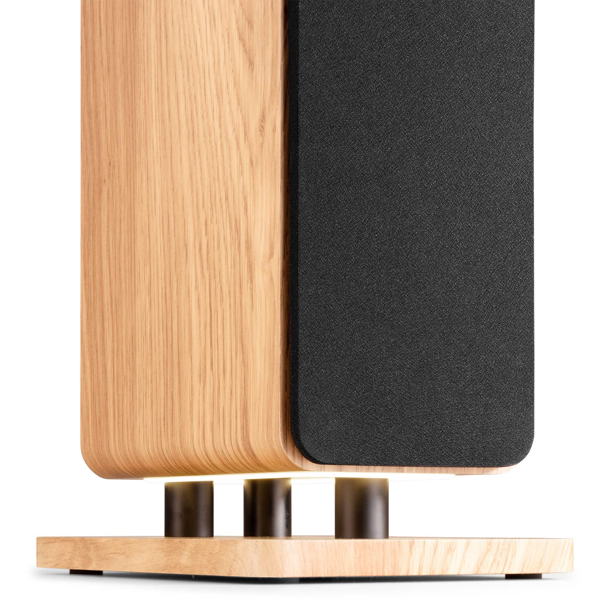 Altavoz de madera con rejilla de tela negra sobre base de madera con tres columnas.