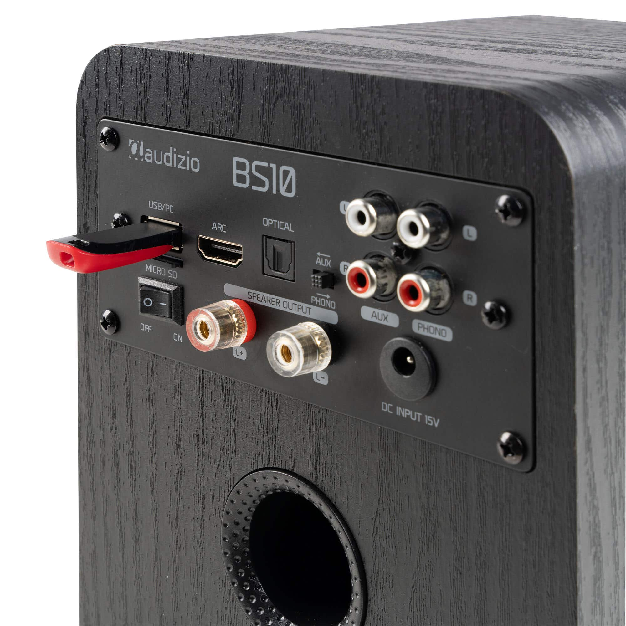 Parte trasera de un altavoz negro con puertos: USB, HDMI, óptico, RCA, entrada CC.