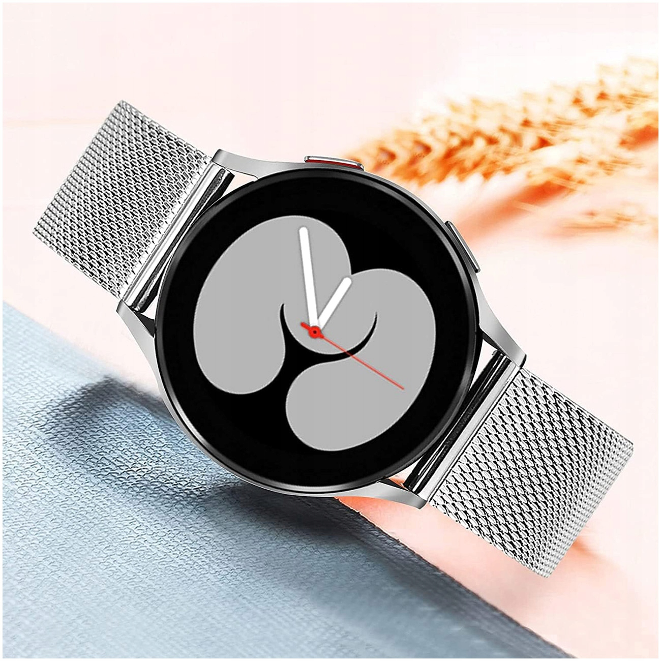 Srebrny smartwatch z siatkowym paskiem i szarą tarczą cyfrową.