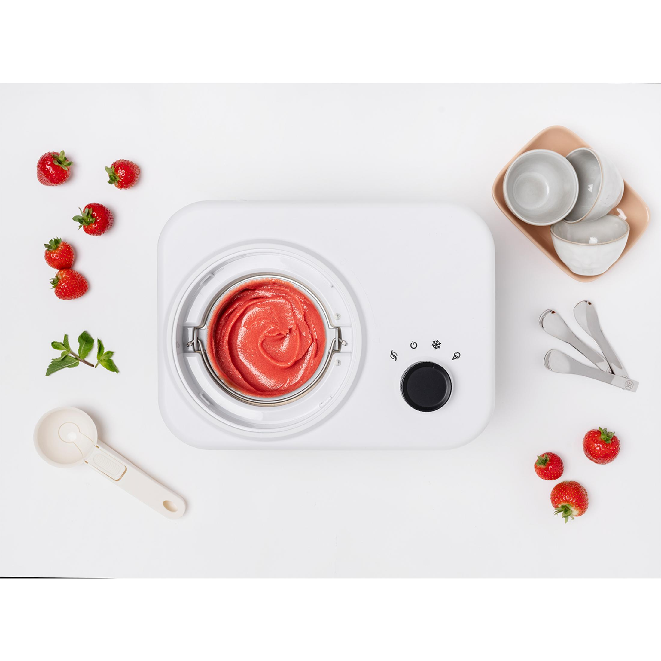 Ein weißer Eisbereiter mit Erdbeer-Sorbet, Erdbeeren, Minze und Schüsselchen.