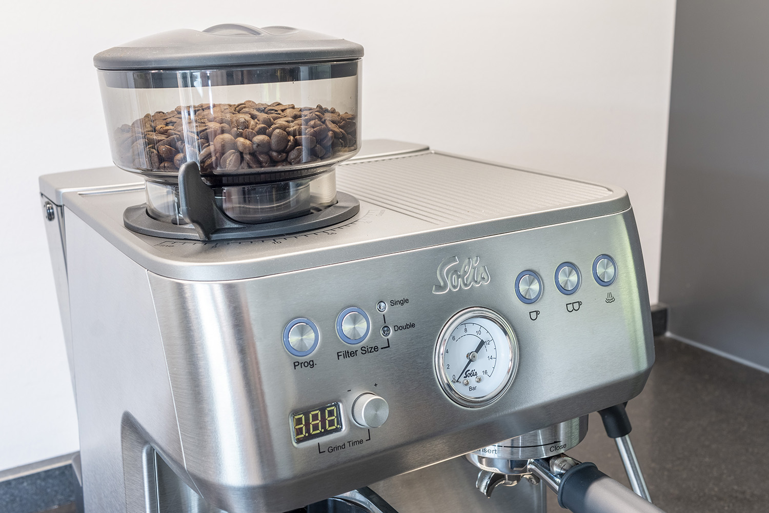 Eine silberne Kaffeemaschine mit Bohnenbehälter, Manometer und Knöpfen.