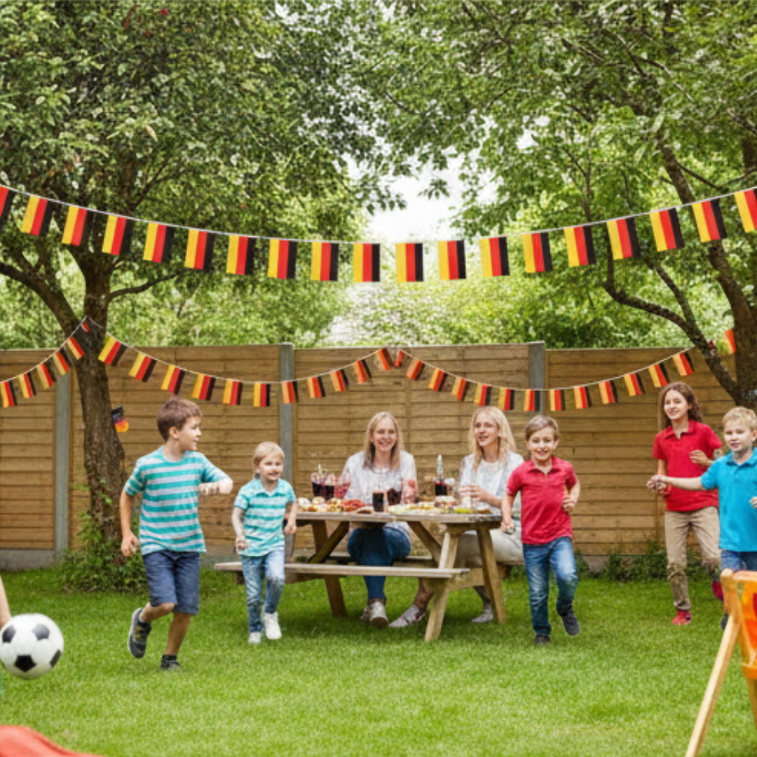 Familie feiert im Garten mit Deutschlandflaggen und Picknick.