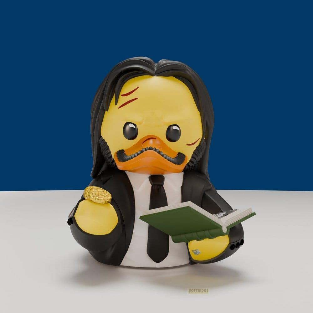 Eine gelbe Quietscheente als John Wick mit schwarzem Anzug, Buch und Münze.