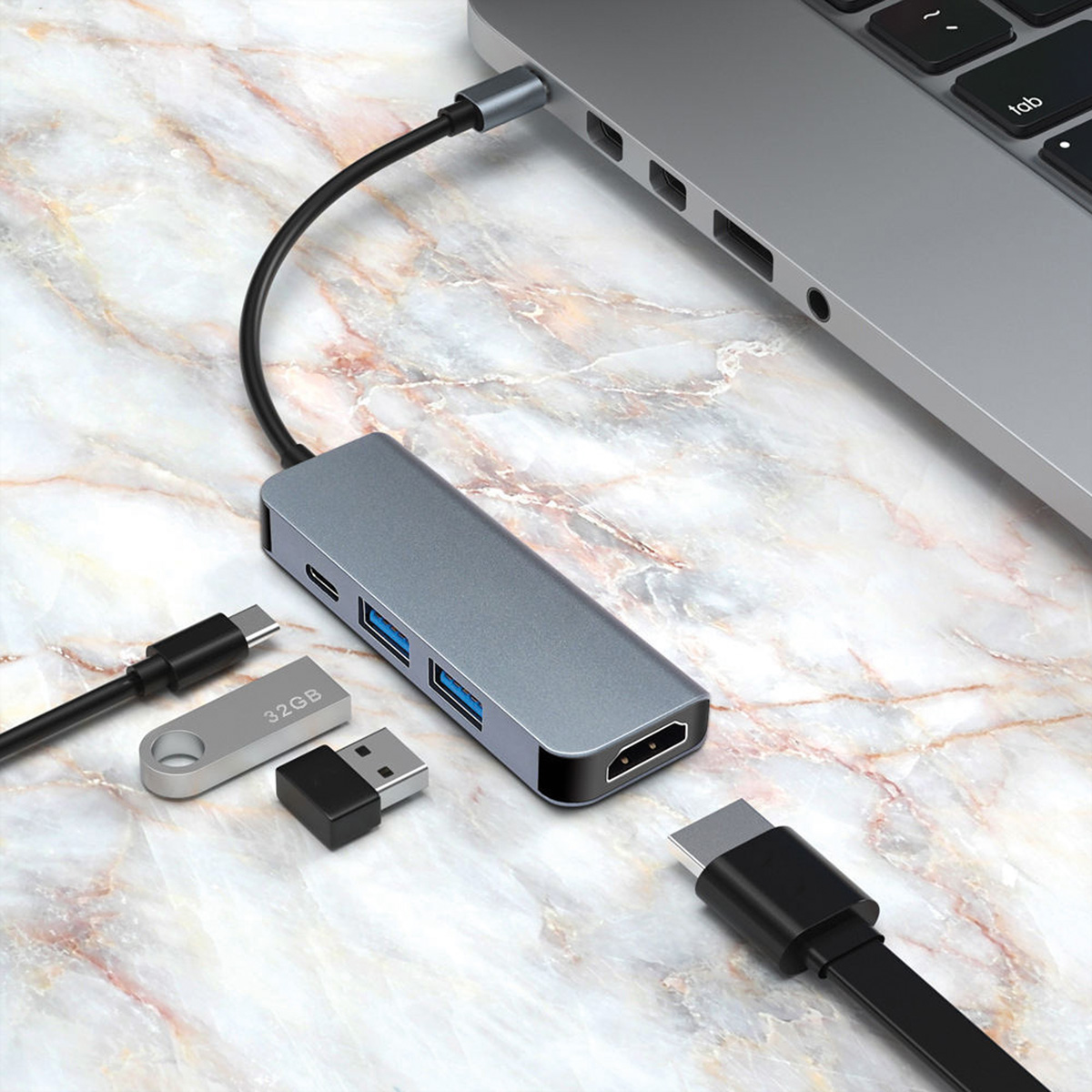 Hub USB-C gris avec ports HDMI et USB, connecté à un ordinateur portable. Clé USB à proximité.