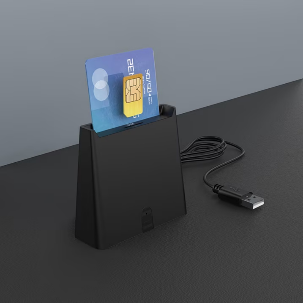 Ein schwarzer SIM-Kartenleser mit einem SIM-Adapter und einem USB-Kabel auf einem dunklen Schreibtisch.