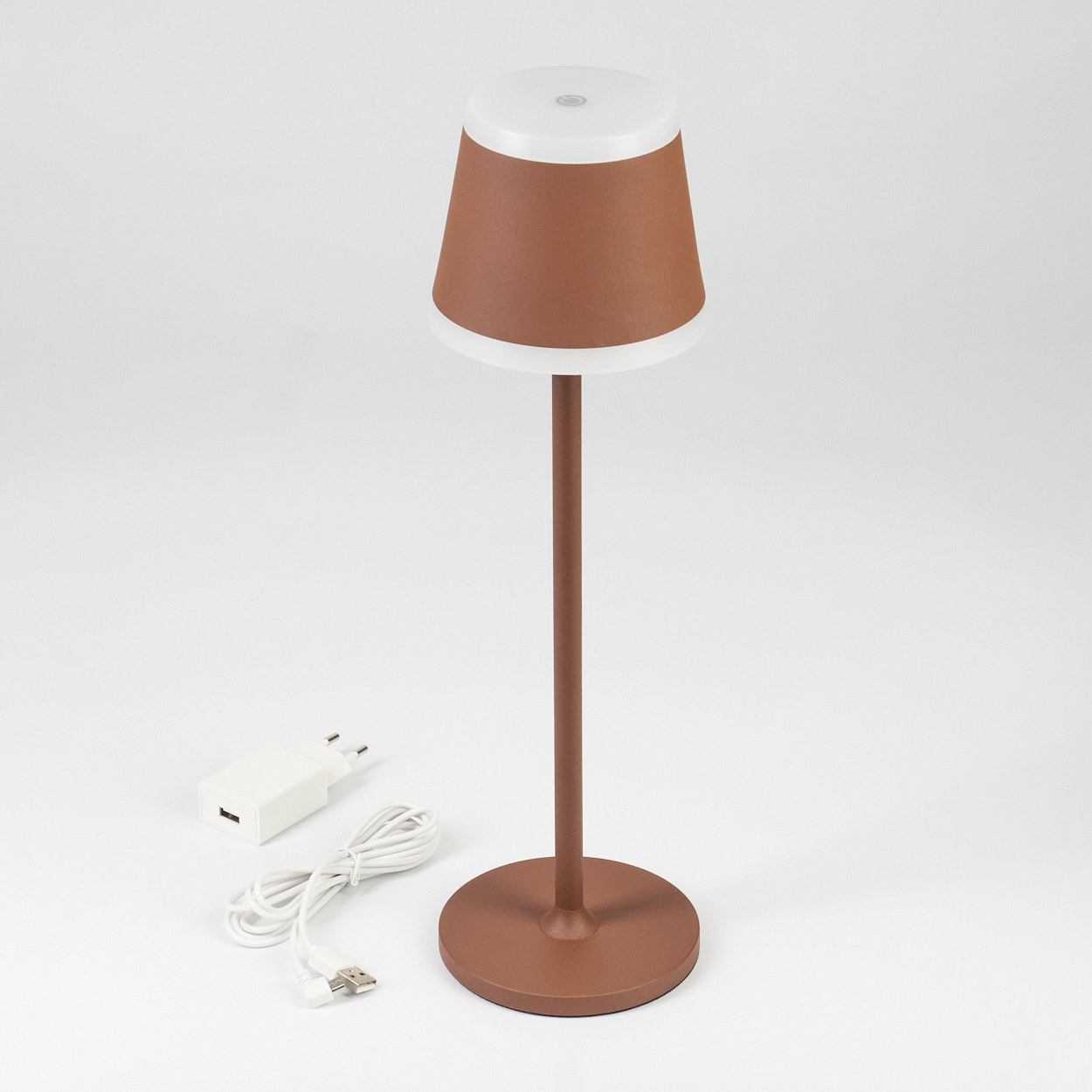 Eine braune Tischlampe mit weißem Schirm und Ladekabel auf weißem Hintergrund.