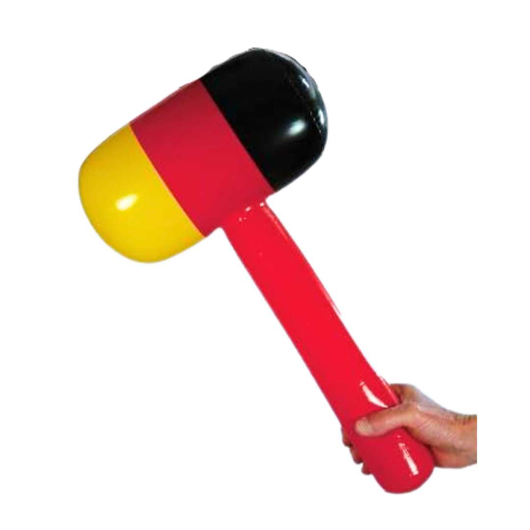 Eine Hand hält einen aufblasbaren Hammer mit den Farben Schwarz, Rot und Gelb.