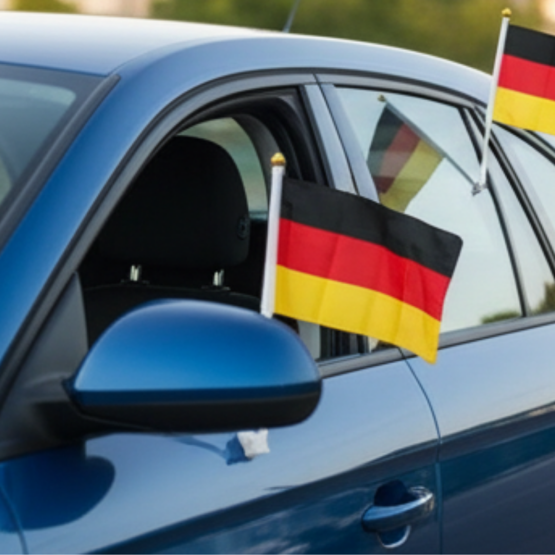 Zwei deutsche Flaggen an einem blauen Auto.