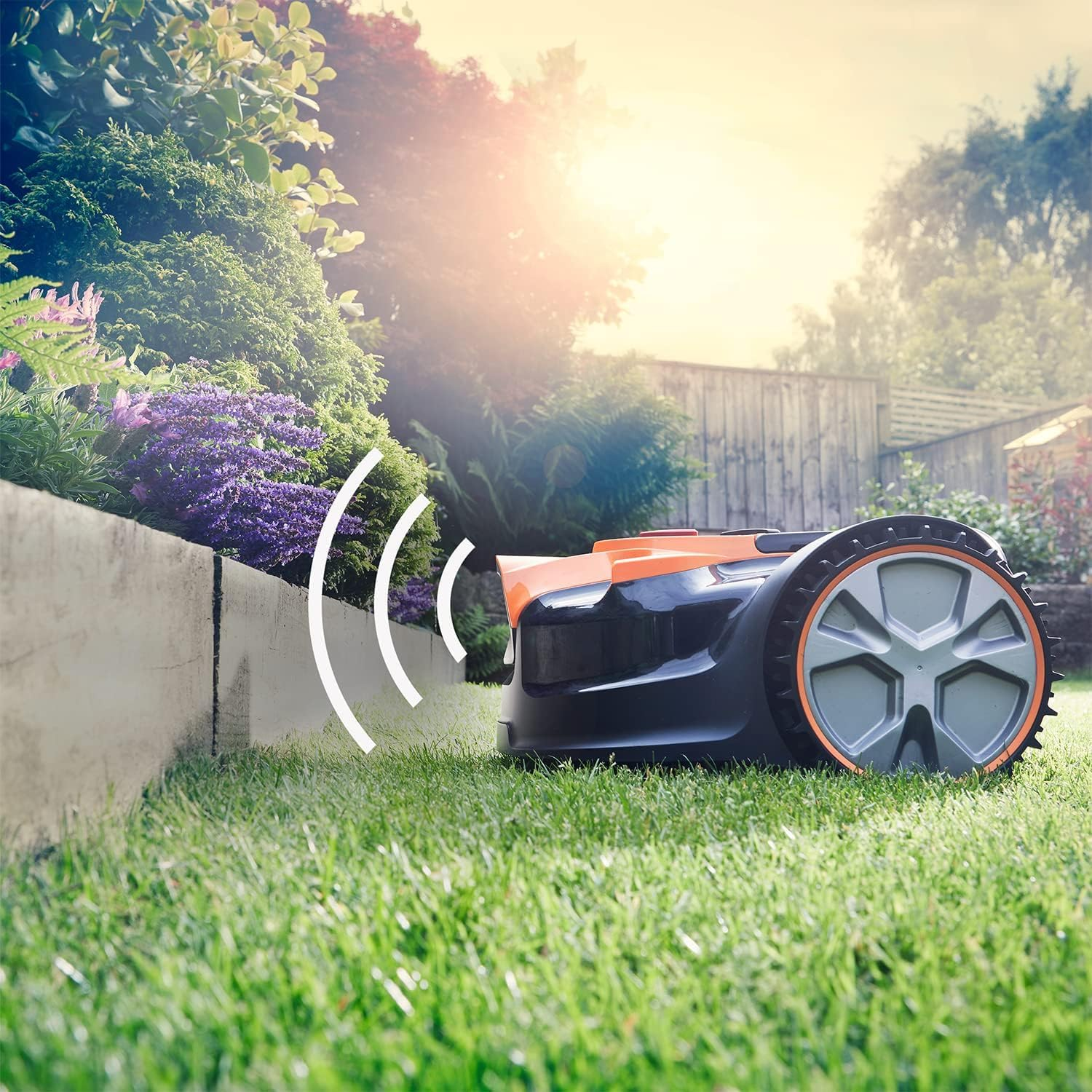 Ein Mähroboter mäht einen gepflegten Rasen neben einem Blumenbeet an einem sonnigen Tag.