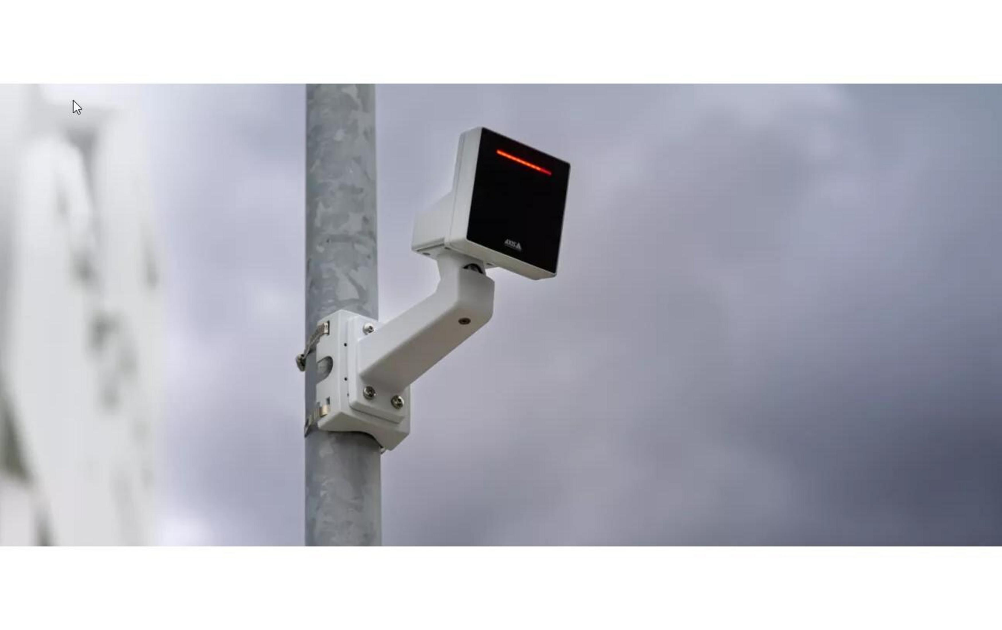 Un appareil blanc avec une barre lumineuse rouge est monté sur un poteau métallique.