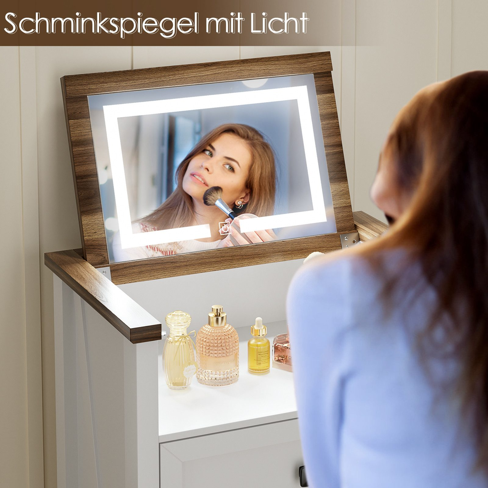 Frau mit Schminkpinsel vor beleuchtetem Spiegel, Parfümflaschen auf der Ablage.