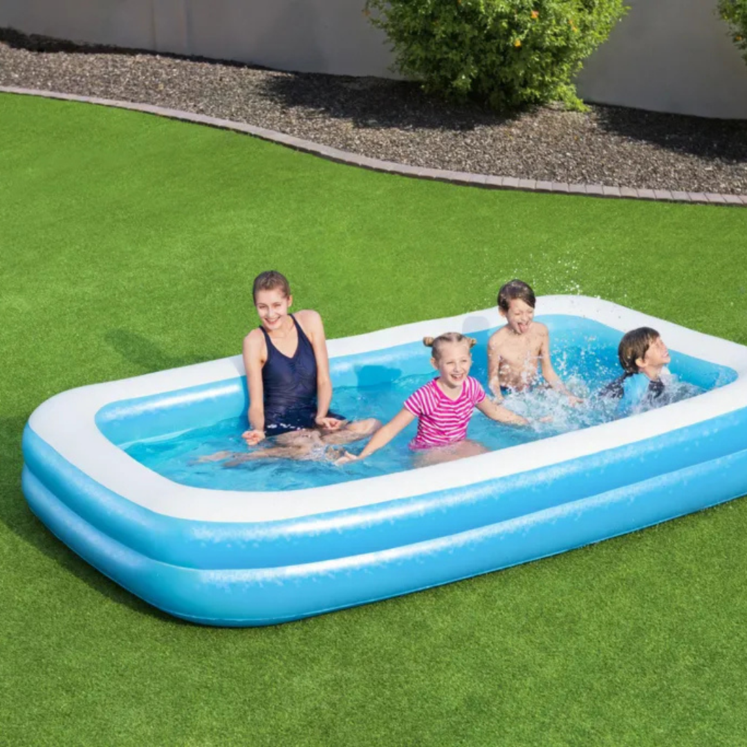 Vier Personen planschen in einem aufblasbaren Pool auf einem grünen Rasen.